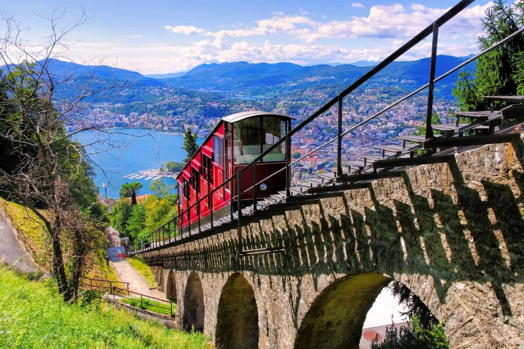 a red train crossing a bridge over a river at Apartments Gelsomino, Orchidea and Magnolia in Castagnola