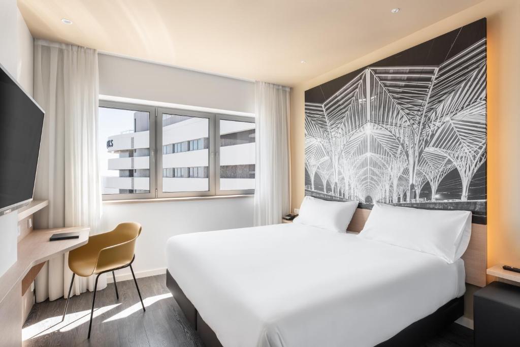 A compact double room pairs a large bed with a window-side desk.