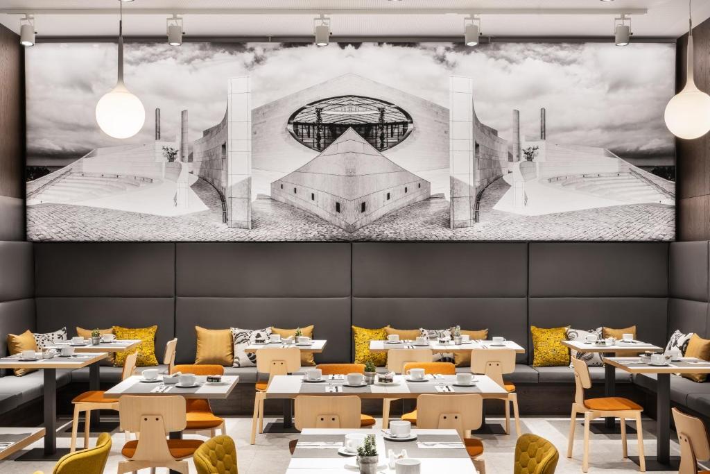 A lively dining room with laid breakfast tables beneath a Lisbon-themed mural.