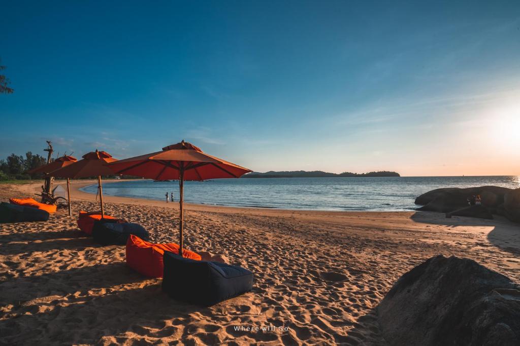 a beach with umbrellas and chairs on the sand at Kalima Resort and Villas Khao Lak in Khao Lak