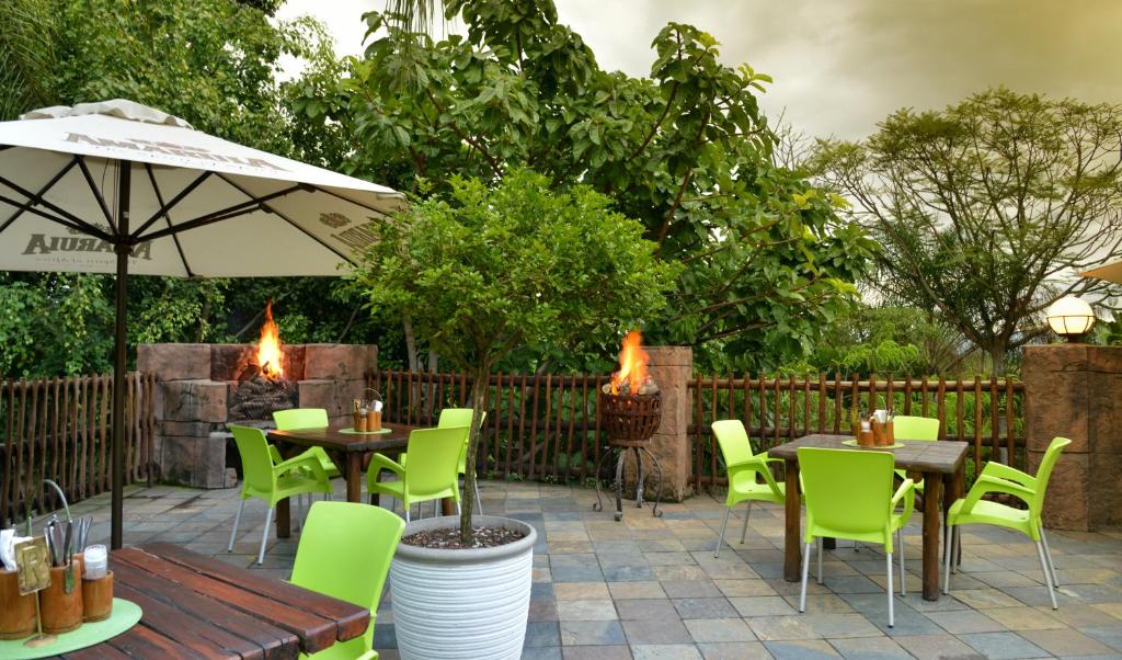 a patio with tables and chairs and an umbrella at eBundu Lodge in White River