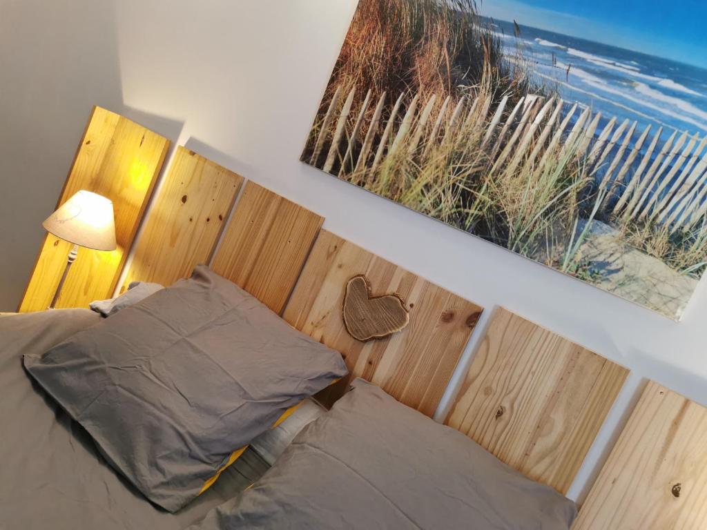 1 cama con cabecero de madera y ventana en Petit havre de tranquillité, en Loudun