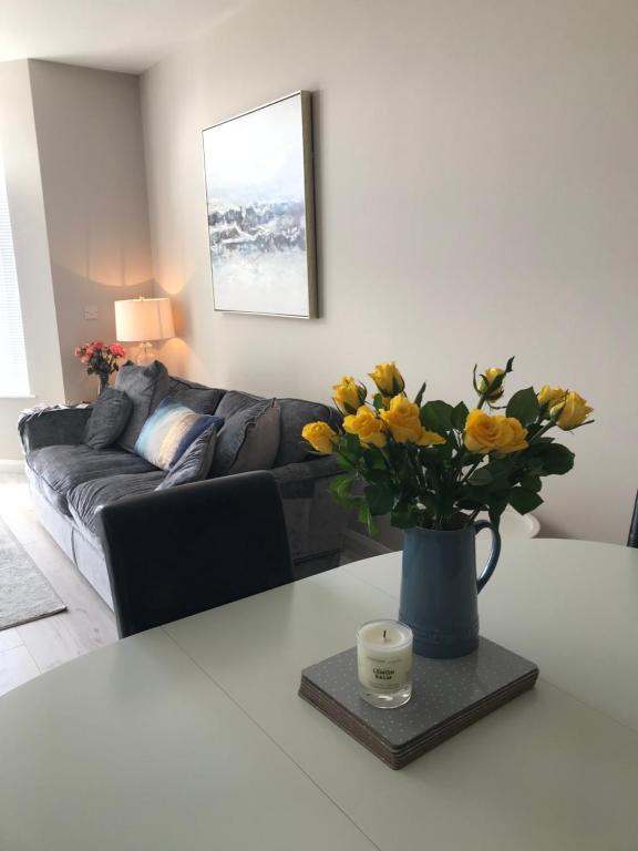 un salon avec un vase de fleurs jaunes sur une table dans l'établissement Apt 1, Whiterocks Portrush, à Portrush