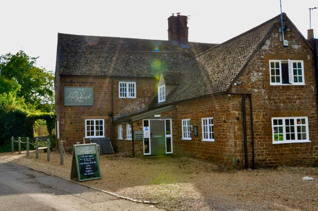 an old brick building with a sign in front of it at The Hollybush Inn and B&B in Priors Marston