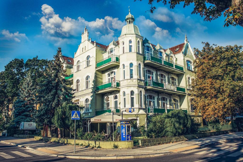 un gran edificio blanco en una calle con árboles en Dom Zdrojowy Amber en Świnoujście