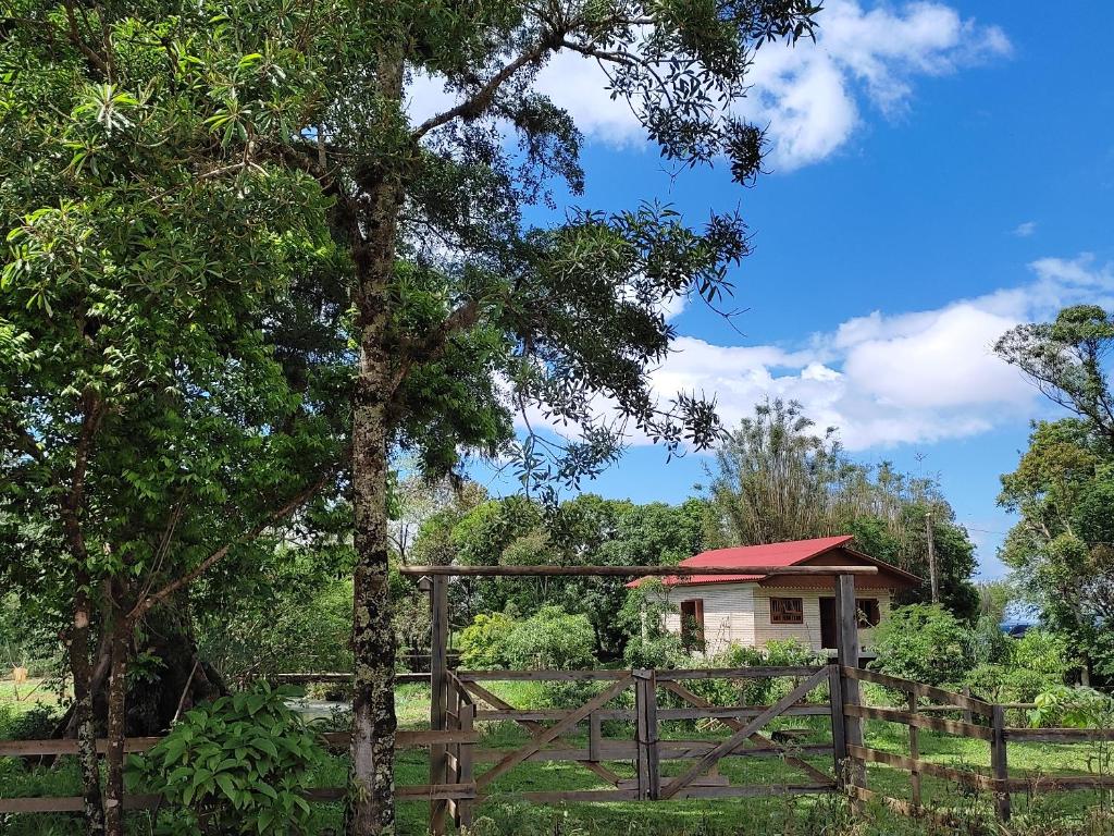 ein kleines Haus mit einem Zaun und einem Baum in der Unterkunft Sítio da Figueira in Praia Grande