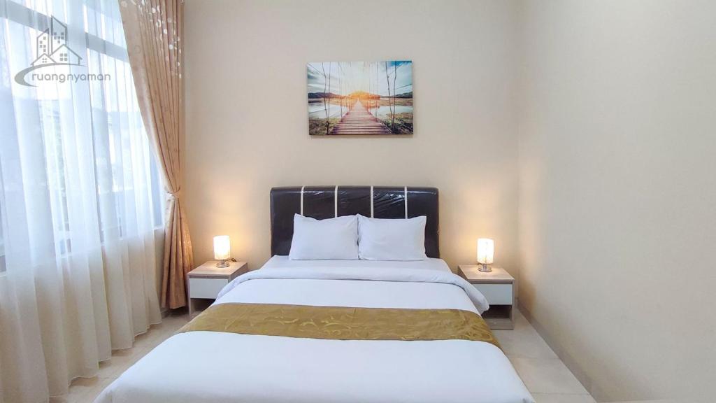 1 dormitorio con 1 cama con 2 lámparas en 2 mesas en Atmosfer Guest House Sentul, en Bogor