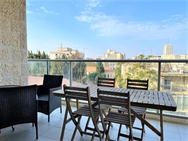 un tavolo in legno con sedie e un balcone con vista. di Best location and family-friendly a Gerusalemme