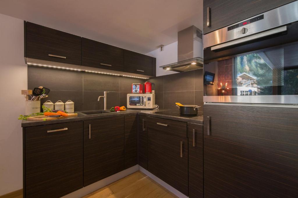 a kitchen with black cabinets and a microwave at Résidence Grand Roc - Bruyères 022 - Happy Rentals in Chamonix