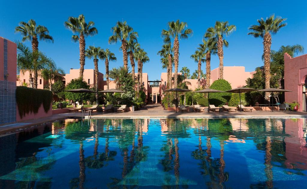 uma grande piscina com palmeiras e guarda-sóis em Hapimag Resort Marrakesh em Douar Soukkane