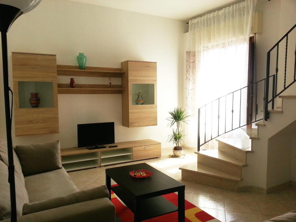 a living room with a couch and a tv and stairs at La Via del Mare - Acireale Centro storico in Acireale