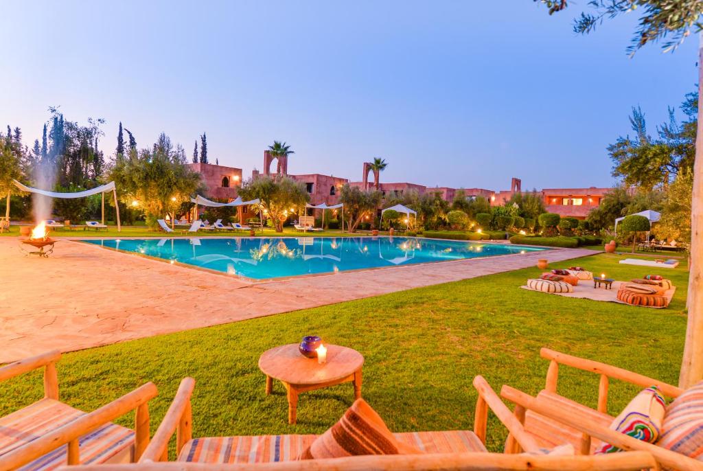 een resort met een zwembad en stoelen in het gras bij Les Jardins De Zyriab in Aït Hamid