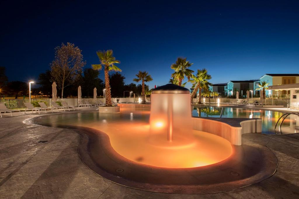 a pool at night with palm trees and a building at Pareus Beach Resort in Caorle
