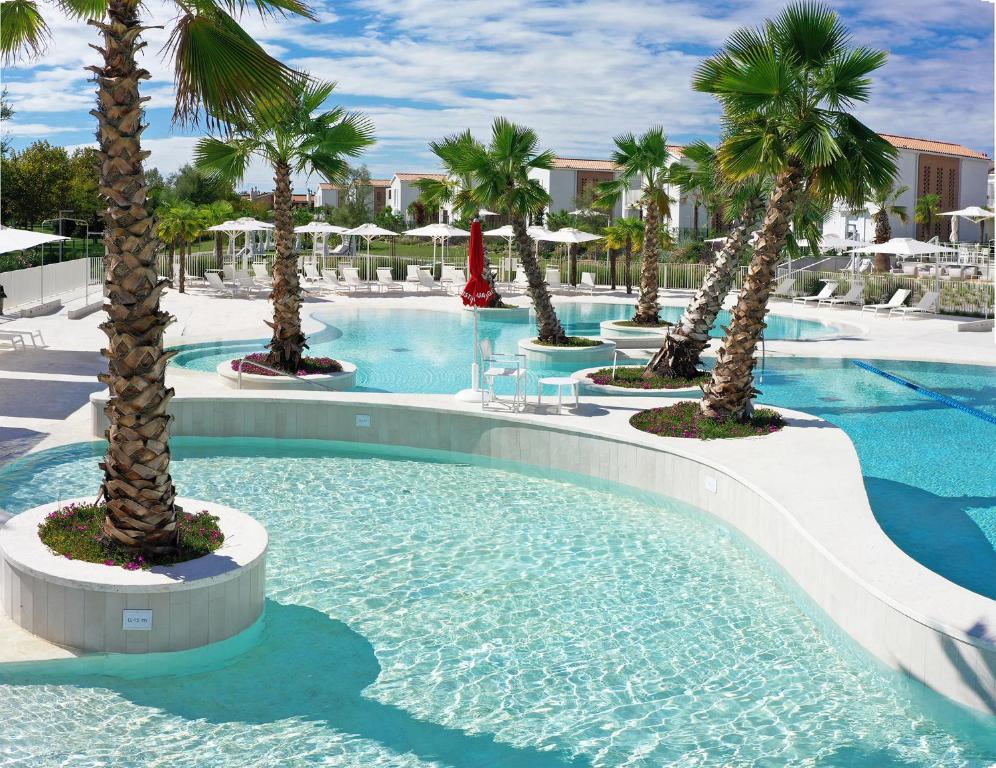 a swimming pool with palm trees and a slide at Pareus Beach Resort in Caorle