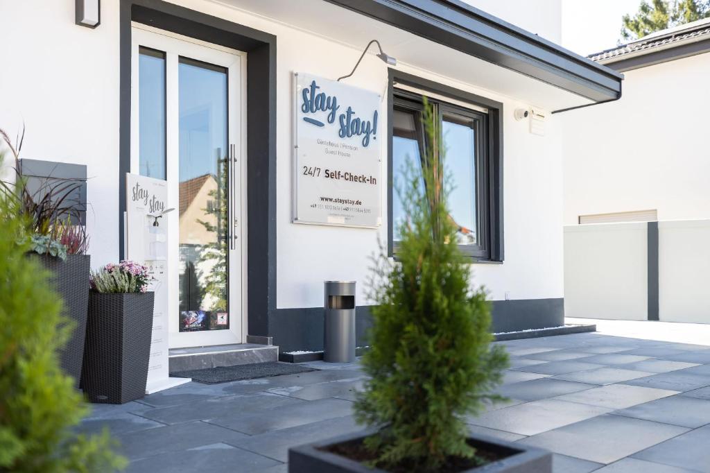 a white building with potted plants in front of it at StayStay Guesthouse I 24 Hours Check-In in Nürnberg