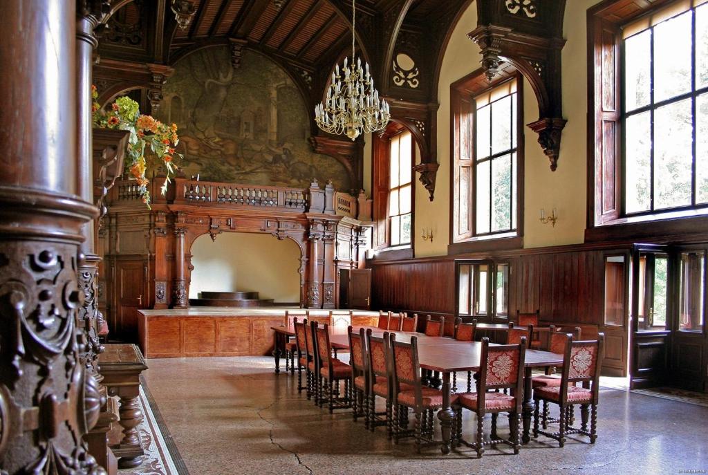 Historic room with large wooden table, ornate chairs, and grand chandelier.