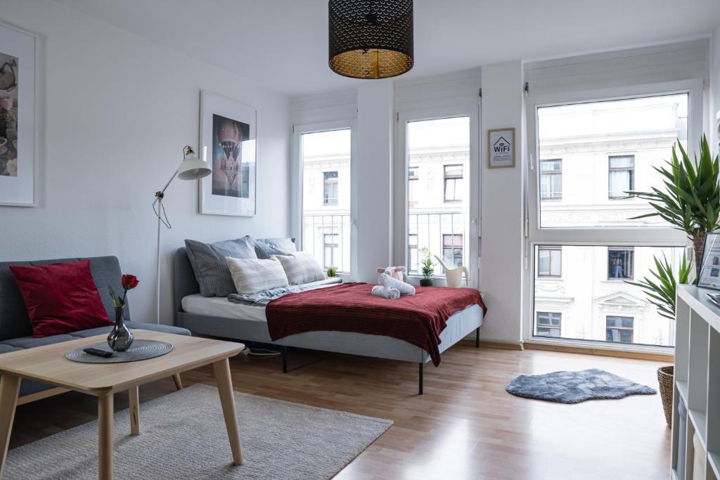 uma sala de estar com uma cama e uma mesa em FULL HOUSE Studios - Southern Prime Apartment em Leipzig