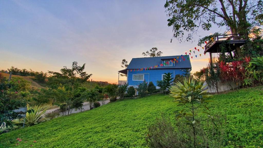 una casa azul sentada en la cima de una colina verde en Tip House en Khao Kho
