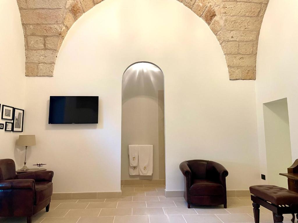a living room with two chairs and a tv on a wall at Villa Di Noi in Arnesano