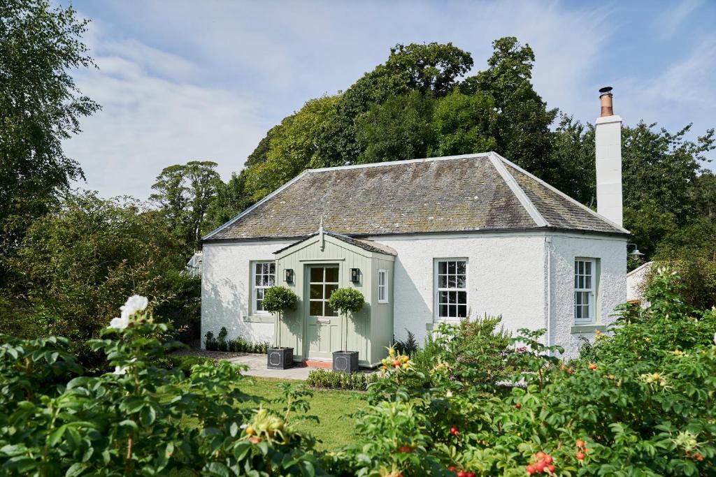 a white house with a chimney and a garden at Balcarres East Lodge in Colinsburgh