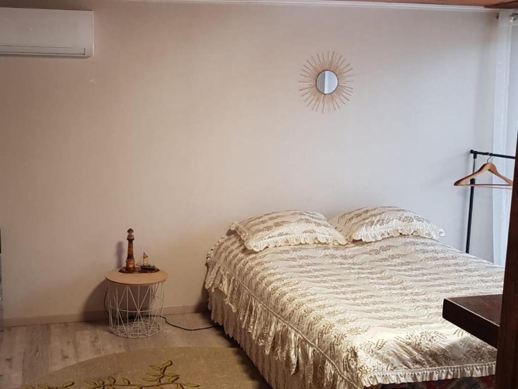 Gîte Des Quinconces في ريشيليو: غرفة نوم مع سرير ومرآة مستديرة على الحائط