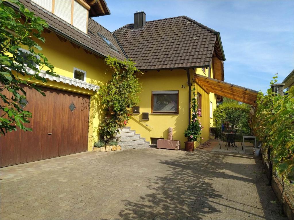 a yellow house with a garage and a driveway at Ferienwohnung Schwörer bis 7 Personen in Rheinhausen