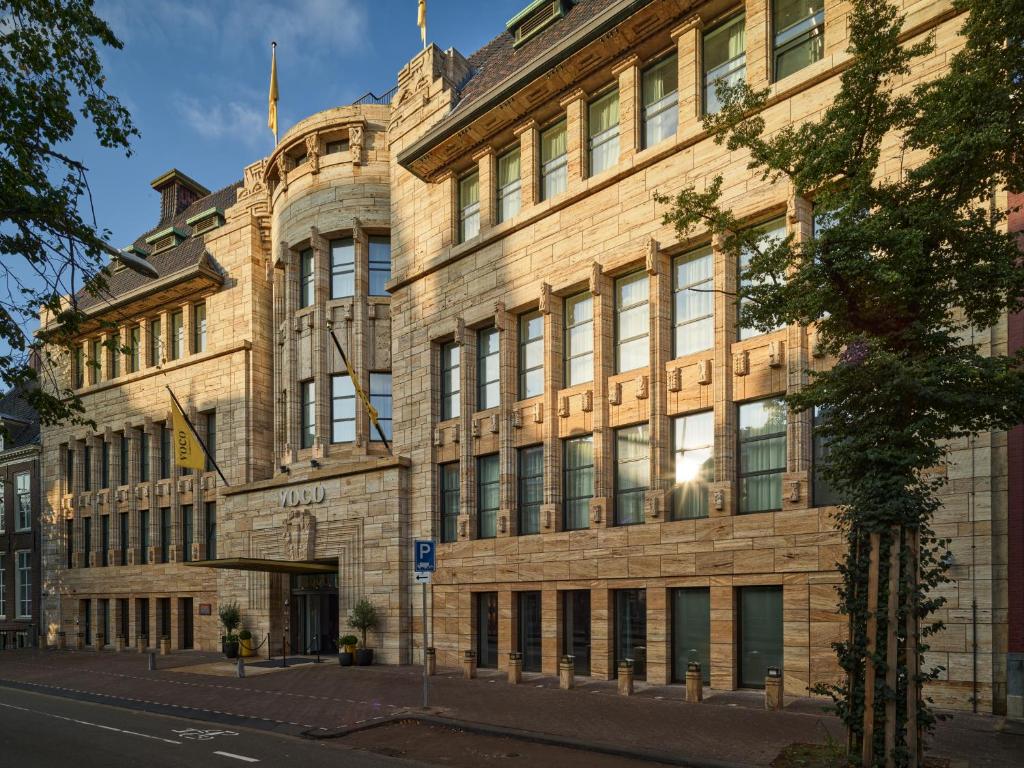 un grand bâtiment en briques au coin d'une rue dans l'établissement voco The Hague, an IHG Hotel, à La Haye