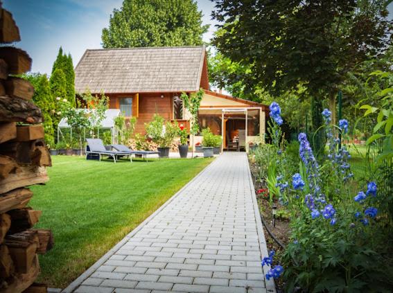 a house with a brick walkway in front of a garden at Hunting Lodge Lipót in Lipót