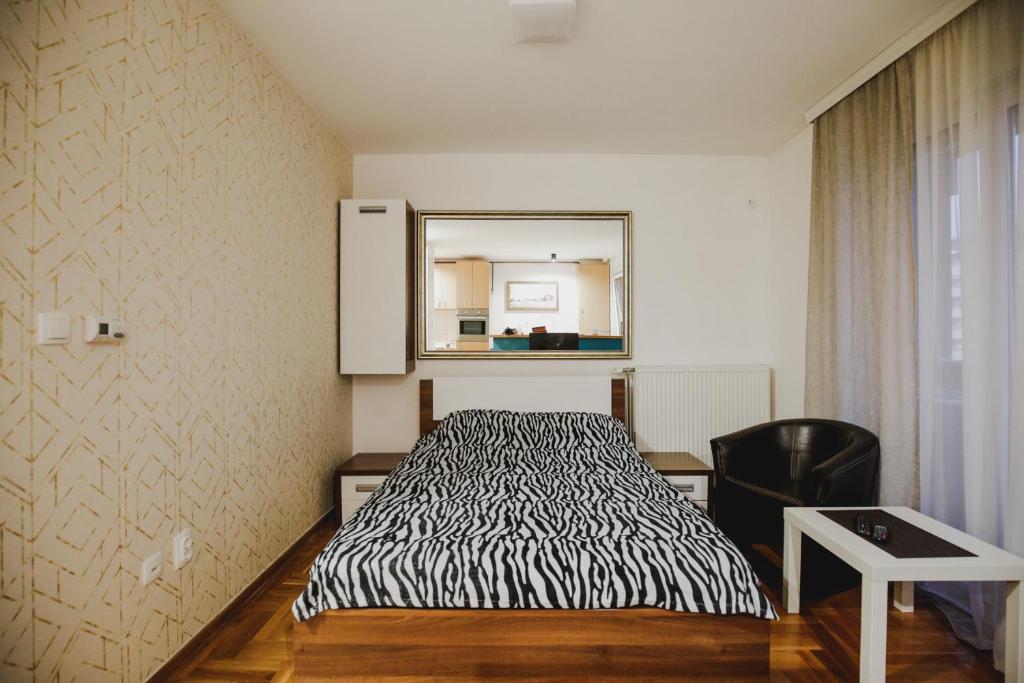 a bedroom with a bed with a mirror and a chair at Prestige apartment in Gornji Milanovac