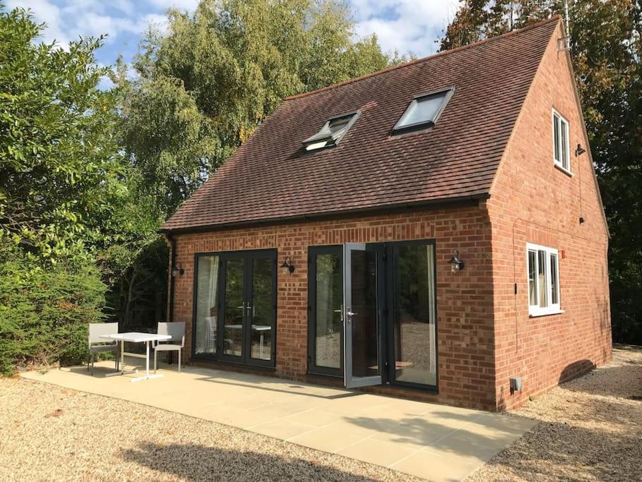 a brick building with glass doors and a table at Contemporary Cottage outside South Harting in South Harting