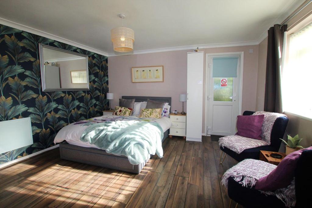 a bedroom with a bed and a chair and a mirror at Peaceful Garden Apartment in Herne Bay