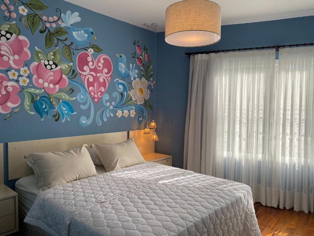 - une chambre avec un lit et un mur fleuri dans l'établissement Apto temático Bauernmalerei Centro Pomerode, à Pomerode