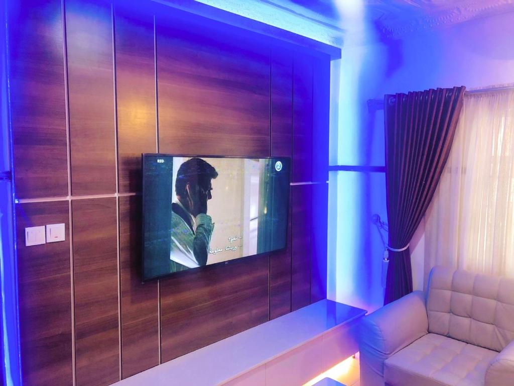 a tv on a wall with a person on it at Presken Hotels @Alade Avenue in Ikeja