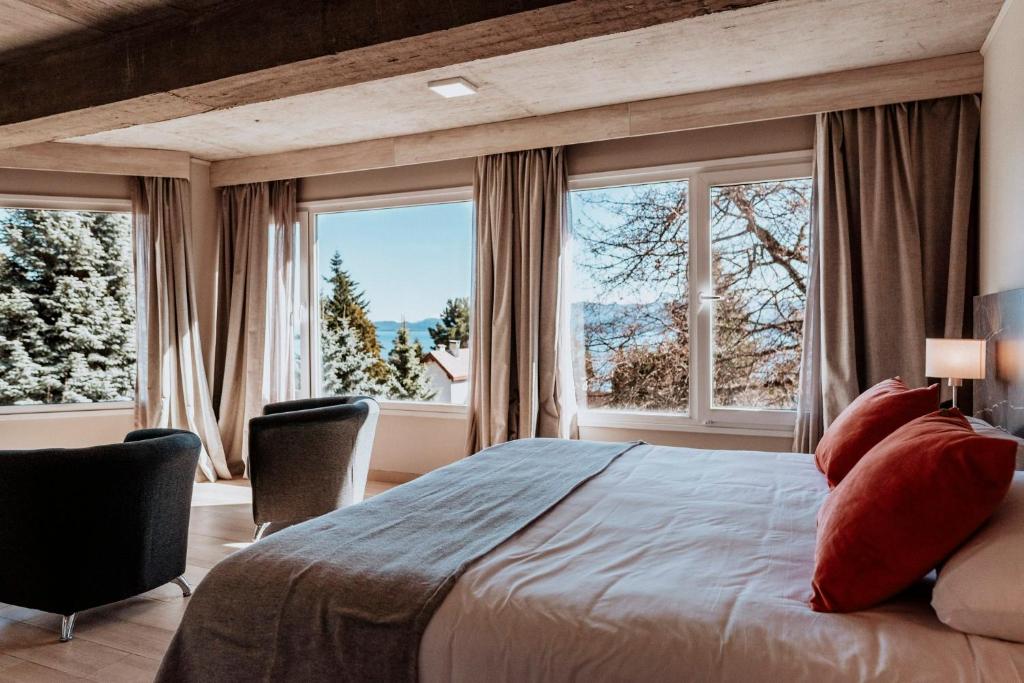 1 dormitorio con 1 cama grande y ventanas grandes en Basia Hotel & Sushi en San Carlos de Bariloche
