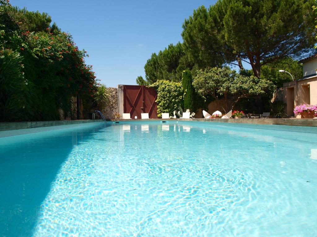 uma grande piscina de água azul num quintal em Le relais d'Angélique em Lunel