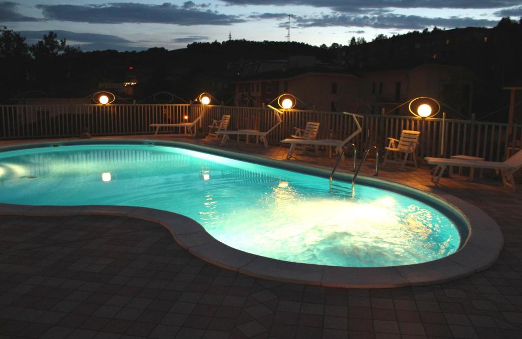 una piscina por la noche con sillas y luces en Hotel Sporting, en Tabiano