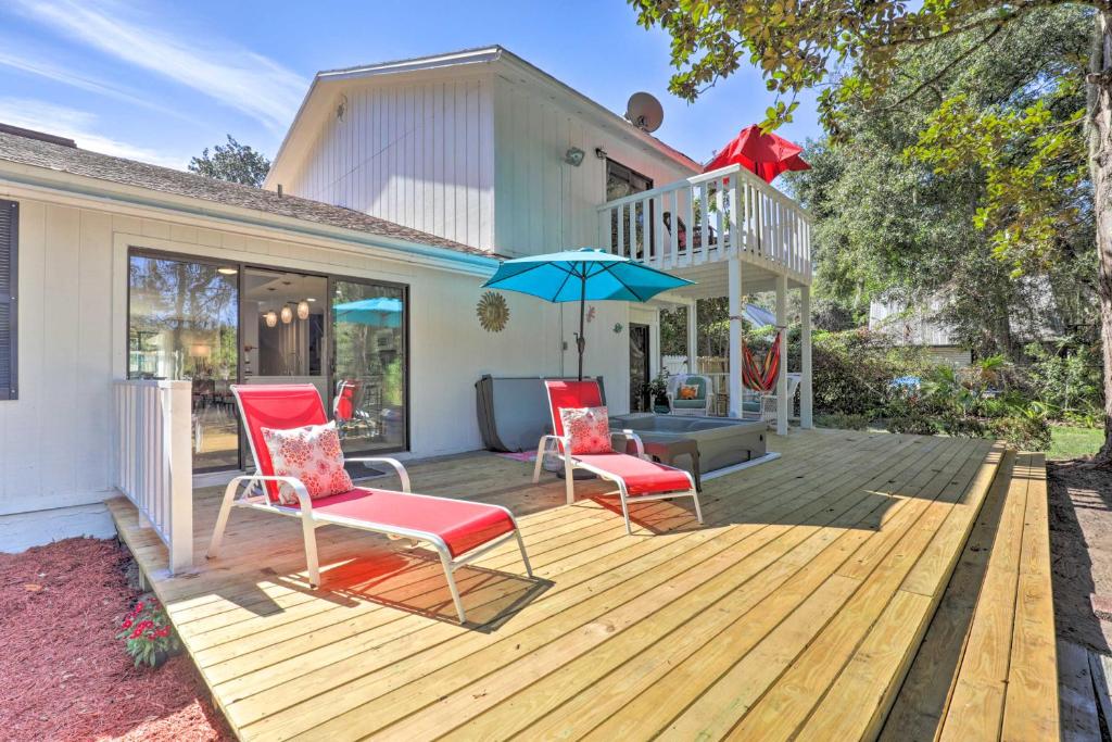 une terrasse en bois avec deux chaises et un parasol dans l'établissement An Acre Paradise with Hot Tub in St Augustine, à Saint Augustine