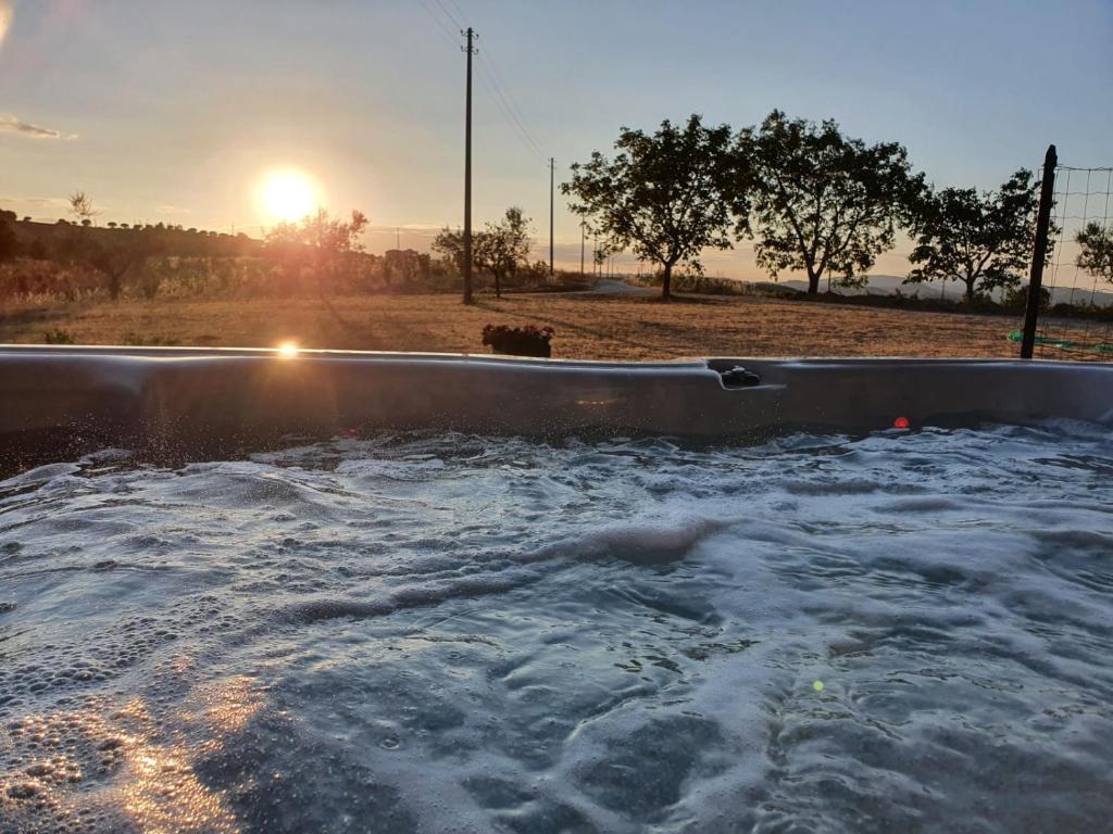 una vasca da bagno riempita d'acqua con il tramonto sullo sfondo di Casale Ziarelli a Brufa