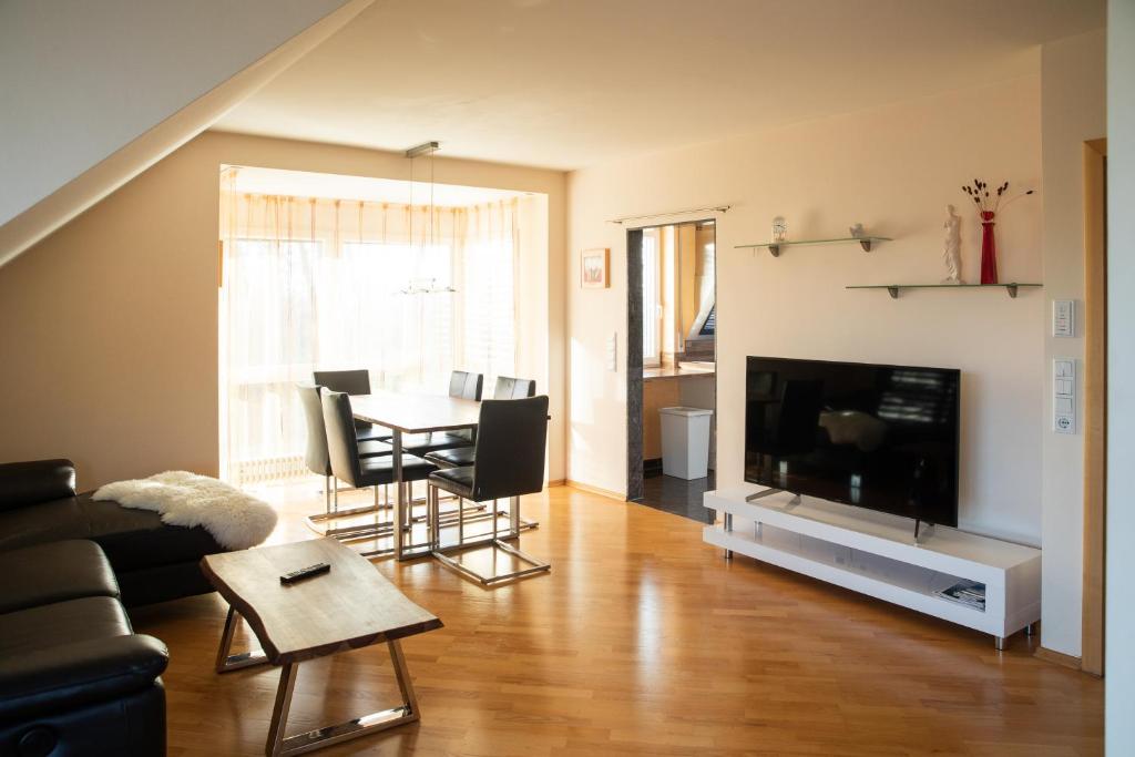 a living room with a table and chairs and a television at Ferienwohnung Ella in Meckenbeuren