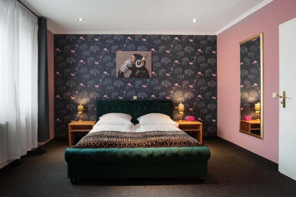 a bedroom with a green bed with a black wallpaper at SmartHotel Flamingo Self check-in in Gießen