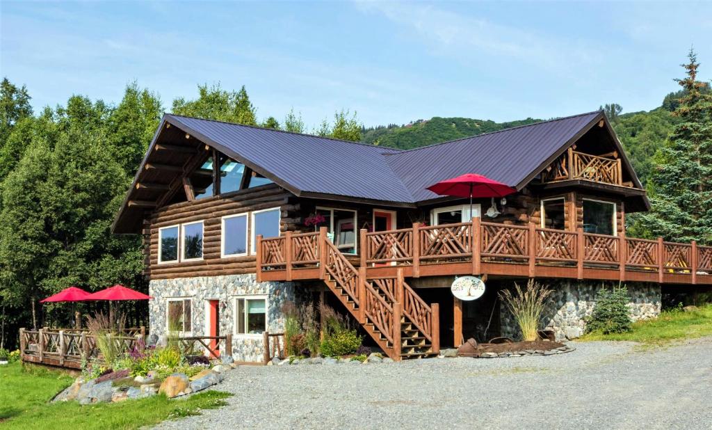 a large log cabin with a balcony and red umbrellas at Juneberry Lodge in Homer