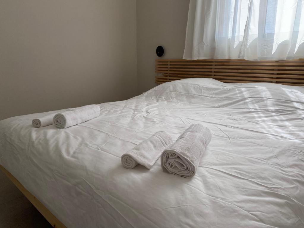 Una cama blanca con tres toallas enrolladas. en מעבר לאופק, en Yeruham