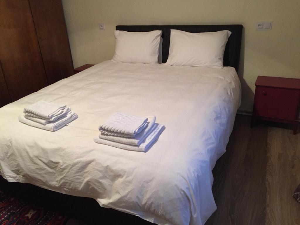 two piles of towels on a white bed at Ethno House inn Tianeti in Tʼianetʼi