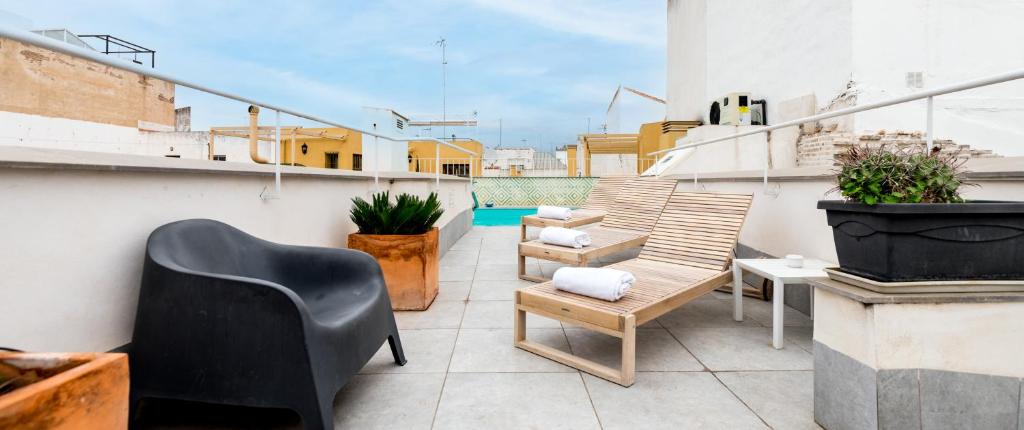 Un balcón con sillas y mesas en un edificio en Apartamentos RG Suites Plaza del Salvador, en Sevilla