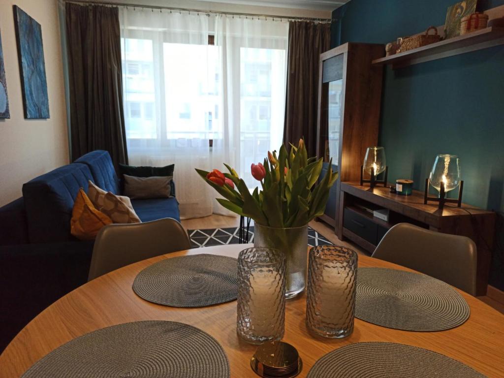 ein Wohnzimmer mit einem Tisch mit Blumen darauf in der Unterkunft MD Apartament Lewandowskiego in Stettin
