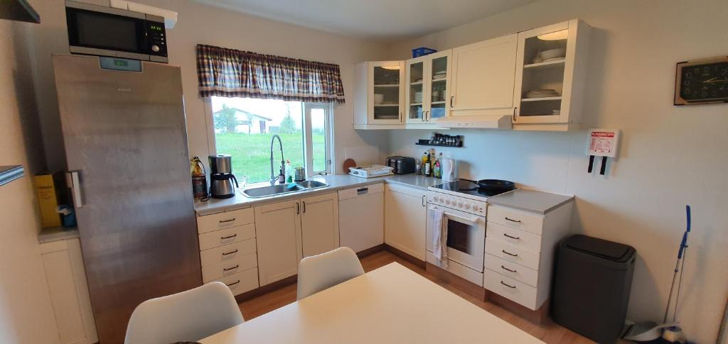 una pequeña cocina con armarios blancos y una mesa en Efri Bru, en Selfoss