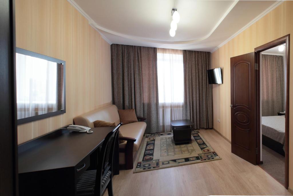a hotel room with a desk and a bedroom at Kristall Hotel in Surgut