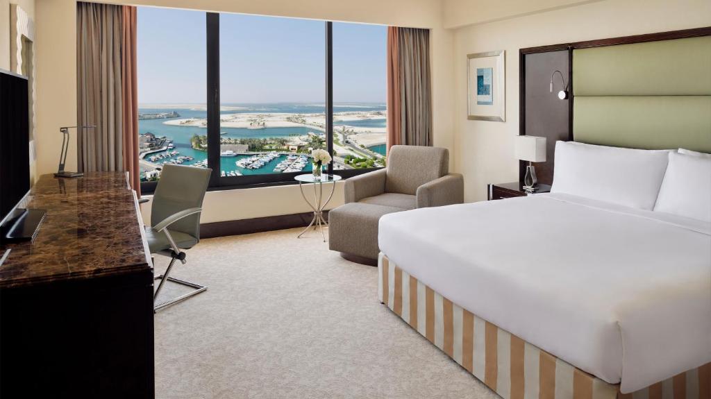 a hotel room with a large white bed and a desk and a couch at InterContinental Abu Dhabi by IHG in Abu Dhabi