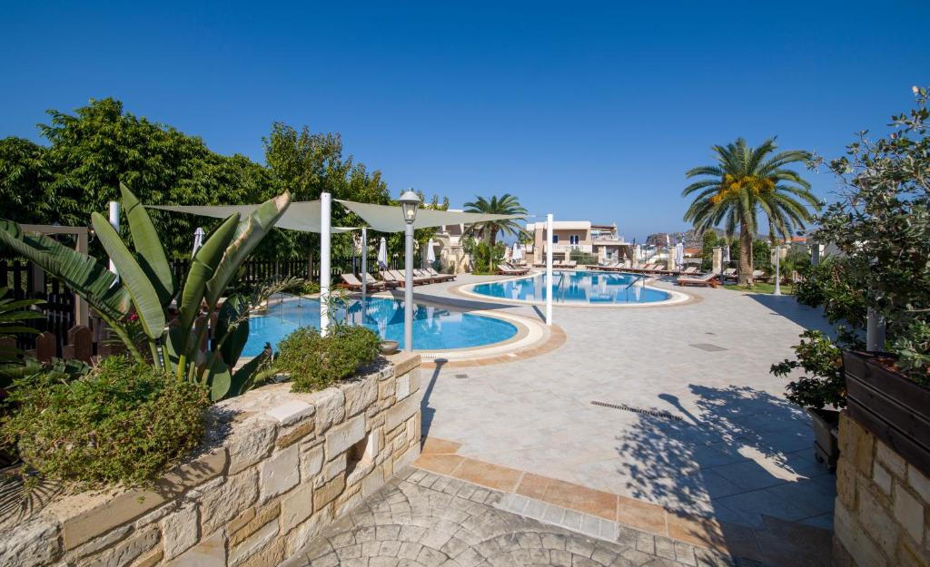 a swimming pool in a resort with palm trees at Isida Hotel Agia Marina in Agia Marina Nea Kydonias