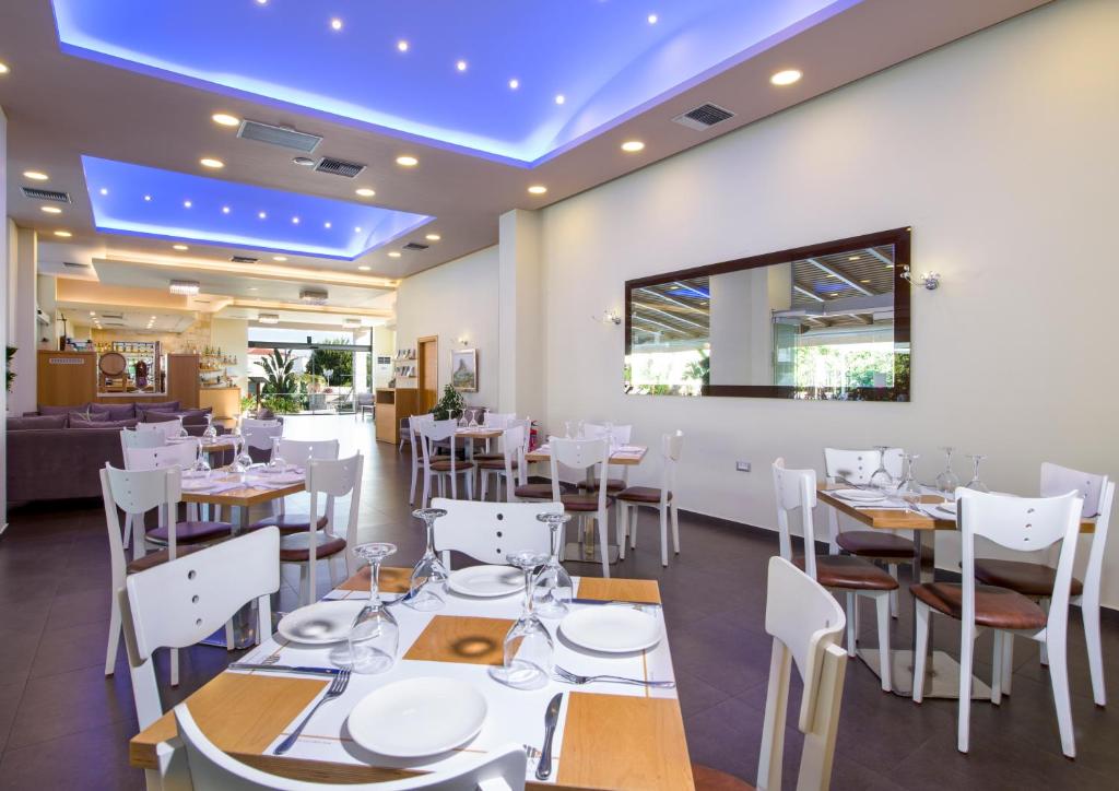 a restaurant with white tables and chairs and a blue ceiling at Isida Hotel Agia Marina in Agia Marina Nea Kydonias